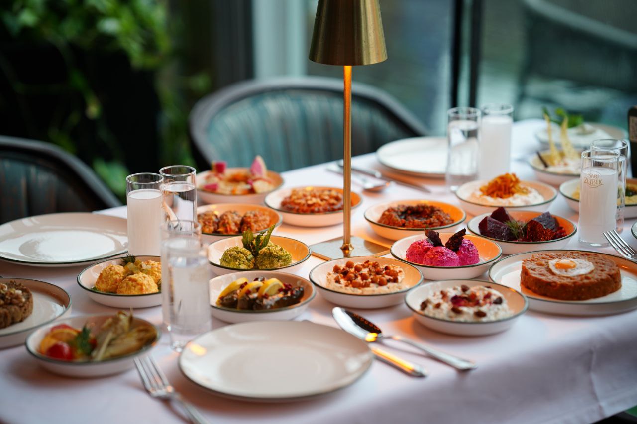 Golab Restaurant’ta yeşil kenarlı tabaklarda mezelerle hazırlanmış sofra